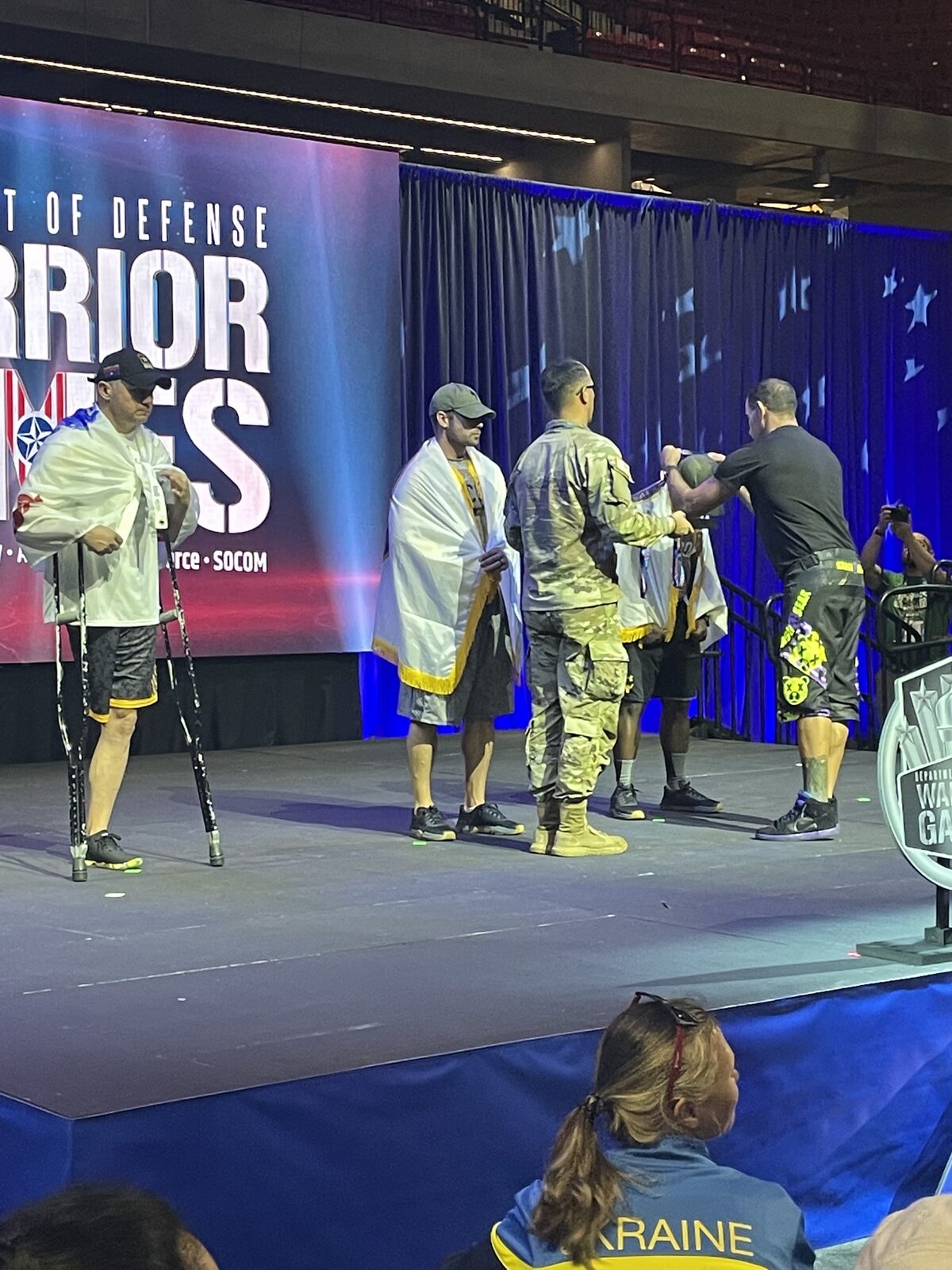Santiago Garcia III placing a medal on a service member on stage at the 2022 Warrior Games